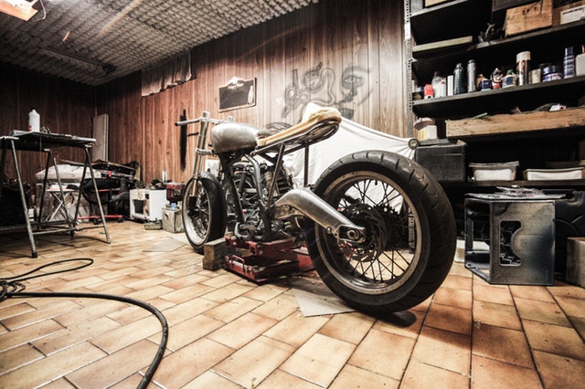 motorka v garáži, kolem je mnoho dalších věcí, starší kousek, který se opravuje